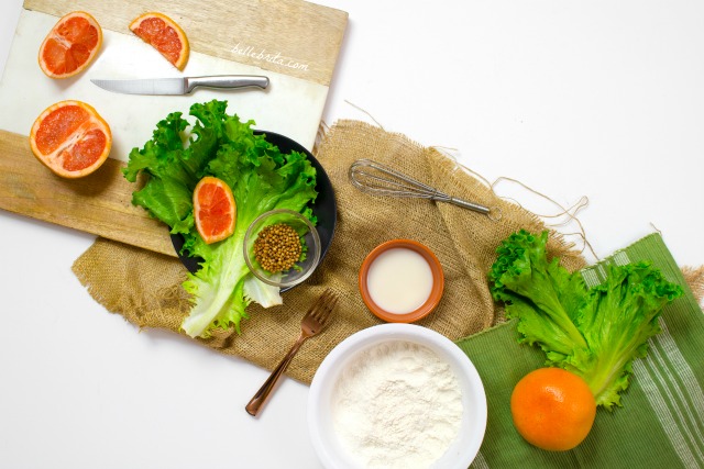 Flat-lay of oranges, green lettuce, and assorted kitchen accessories.