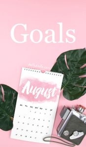 Pink flat lay with August calendar and green leaves. Text overlay reads Goals.