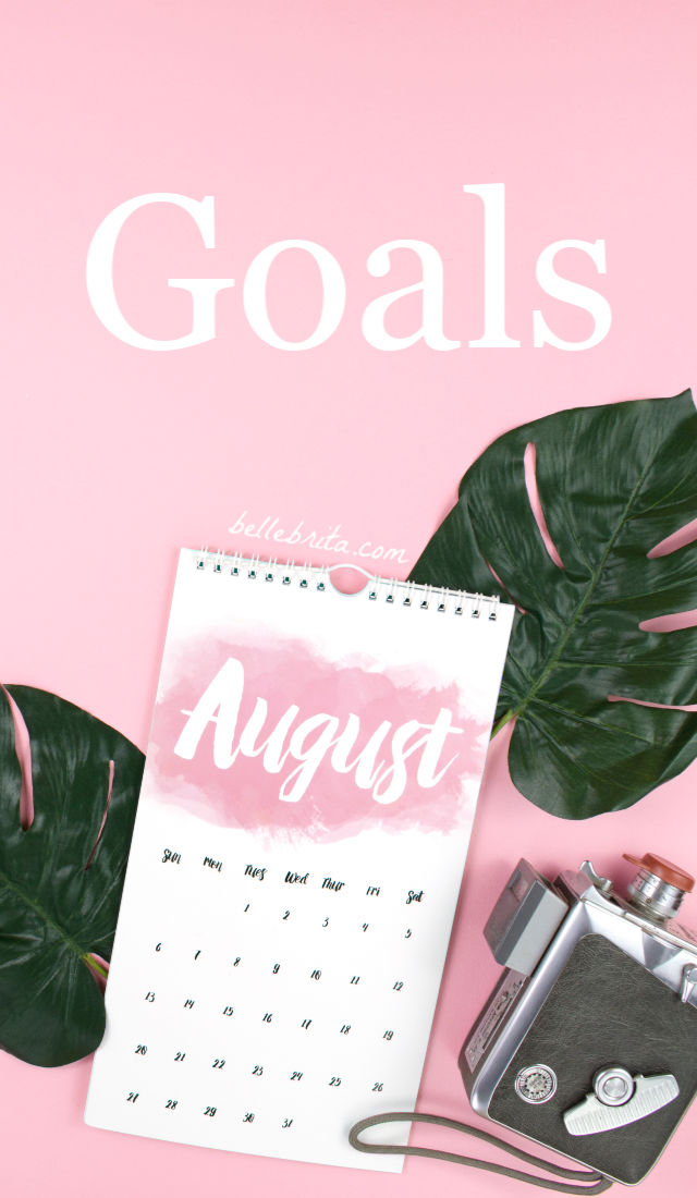 Pink flat lay with August calendar and green leaves. Text overlay reads Goals. 