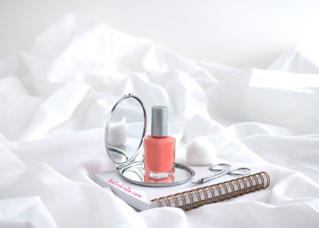 Coral nail polish, white notebook, beauty supplies, white blanket. 