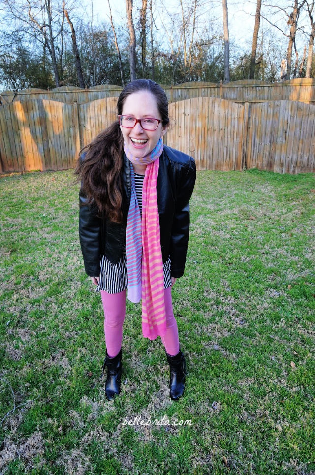 White woman laughing, wearing pink Pact leggings, standing in green yard.