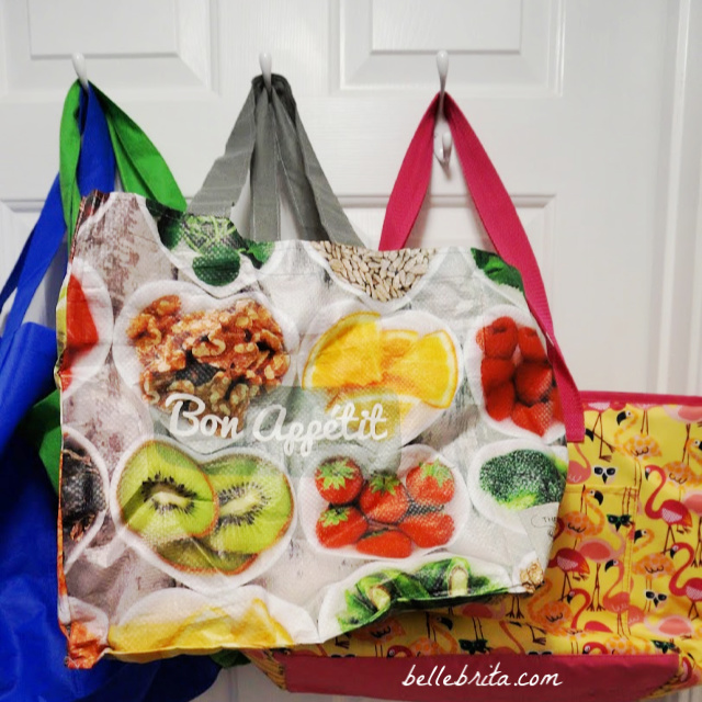 Colorful reusable grocery bags hanging on a door, another of my favorite one-use plastic alternatives