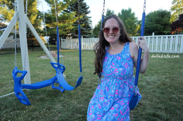 White woman wearing Lilly Pulitzer dress on swing set