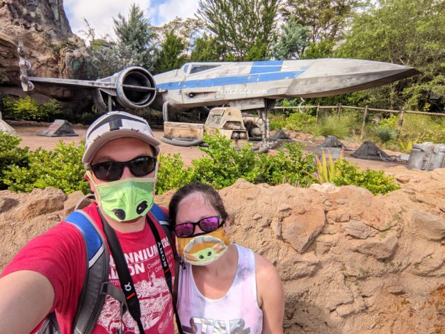White man and white woman wearing Baby Yoda face masks in Galaxy's Edge at Hollywood Studios
