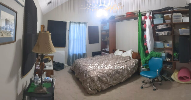 Before photo of a guest bedroom. Shows lamps, window, Murphy bed, shelving, and a mess. 